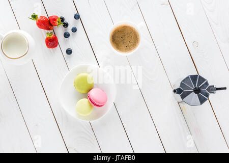 Vista dall'alto di macarons con caffè e fragole sul piano portapaziente in legno Foto Stock