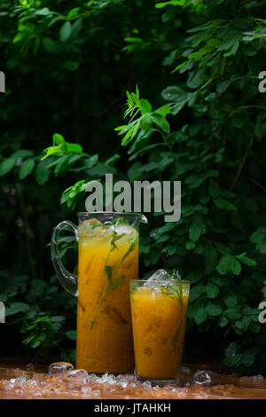 Limonata di agrumi con erbe su uno sfondo di legno. Limonata arancione al dragoncello Foto Stock