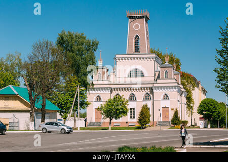 Chachersk, Bielorussia - 14 Maggio 2017: Giovane Donna che cammina sulla strada vicino al Vecchio Municipio nella soleggiata giornata estiva. Municipio di Chechersk Foto Stock