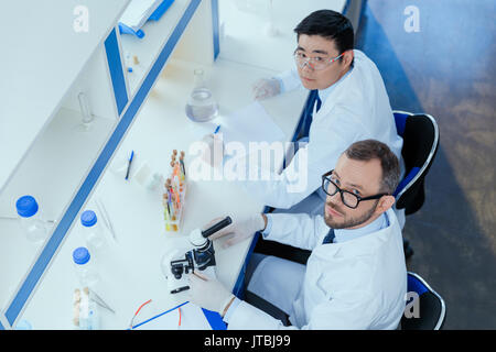 Angolo di Alta Vista della farmacia di occhiali e camici da laboratorio a lavorare insieme nel laboratorio chimico Foto Stock