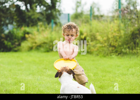 Kid e il cane giocando Tug-of-war game con disco giocattolo Foto Stock