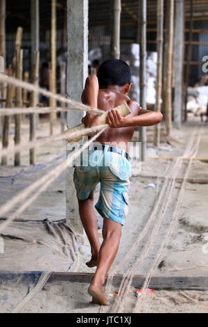 Bambino fatiche lavorando in una corda manufacturing factory a Keraniganj a Dhaka il 09 giugno 2013. Foto Stock