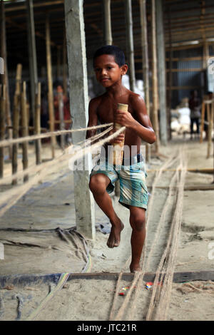 Bambino fatiche lavorando in una corda manufacturing factory a Keraniganj a Dhaka il 09 giugno 2013. Foto Stock