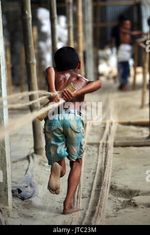 Bambino fatiche lavorando in una corda manufacturing factory a Keraniganj a Dhaka il 09 giugno 2013. Foto Stock