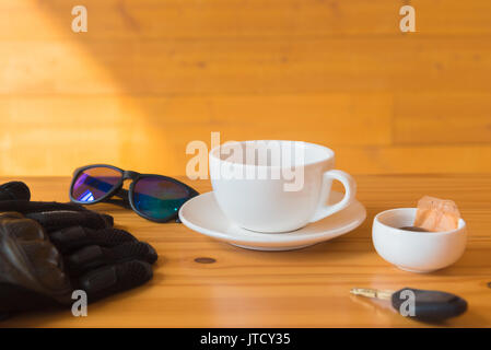 Guanto guida e bicchieri posto vicino a tazza da tè sul tavolo di legno Foto Stock