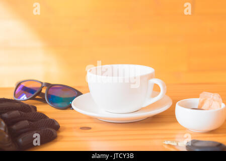 Guanto guida e bicchieri posto vicino a tazza da tè sul tavolo di legno Foto Stock