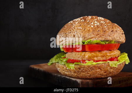 Hamburger fatti con carne, lattuga, pomodoro, ketchup e semi bun, su sfondo nero. Foto Stock