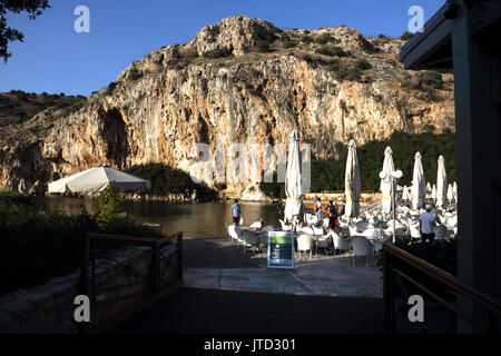 Vouliagmeni Atene Grecia turisti che nuotano nel lago Vouliagmeni una spa naturale - una volta era una caverna ma il tetto della grotta è caduto a causa dell'erosione del Foto Stock