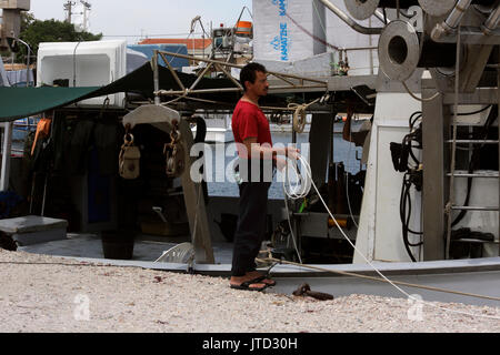 Lavrio Port Attica Grecia uomo legando la pesca in barca Foto Stock