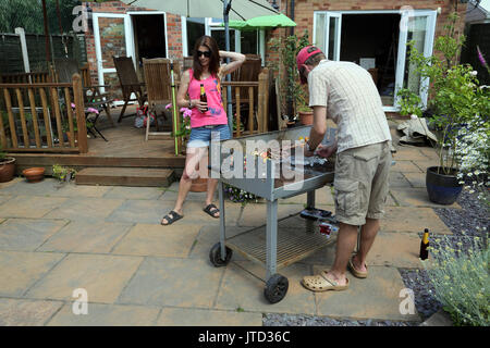 Famiglia avente un barbecue in giardino durante i mesi estivi Birmingham West Midlands England Foto Stock