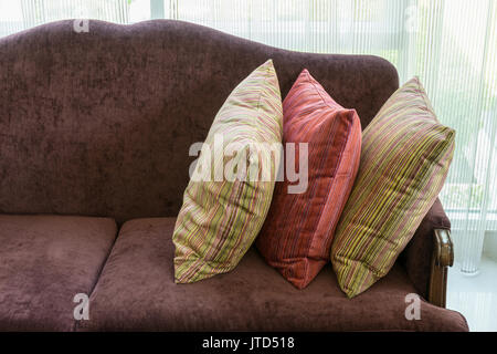 A strisce colorate di cuscini sul divano rosso in luxury living room interior Foto Stock