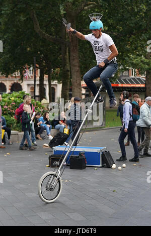 Un juggling unicyclist scende dal suo ciclo in Leicester Square a Londra. Da una serie di quadri di artisti di strada a Londra, Regno Unito. Data foto Foto Stock