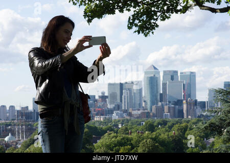 Donna sorge nella parte sud di Londra con la City di Londra e le viste di Canary Wharf in background in una giornata di sole con il cielo blu e nuvole Foto Stock