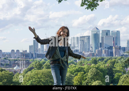 Donna sorge nella parte sud di Londra con la City di Londra e le viste di Canary Wharf in background in una giornata di sole con il cielo blu e nuvole Foto Stock