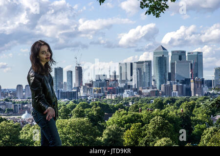 Donna sorge nella parte sud di Londra con la City di Londra e le viste di Canary Wharf in background in una giornata di sole con il cielo blu e nuvole Foto Stock