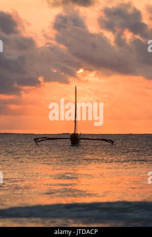 Barca Dhow stagliano in inizio di mattina di rottura alla luce del sole attraverso le nuvole oltre oceano Indiano, Diani, Kenya