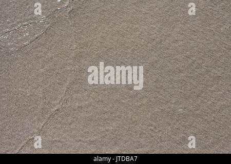 Onda morbida di colore blu oceano su una spiaggia di sabbia. Sfondo. Messa a fuoco selettiva. Foto Stock