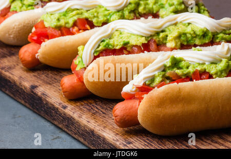 Cileno Completo Italiano. Hot Dog panini con pomodoro, avocado e maionese sulla tavola di legno. primo piano. Foto Stock