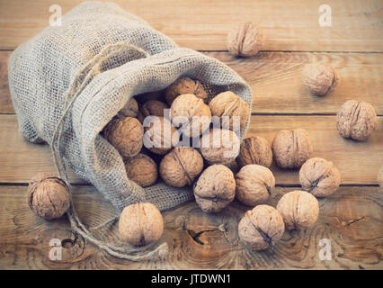 Le noci in un sacchetto su un sfondo di legno Foto Stock