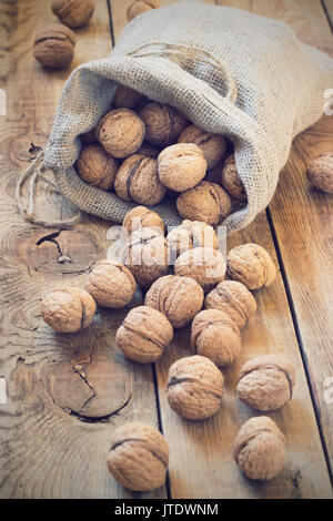 Le noci in un sacchetto su un sfondo di legno Foto Stock