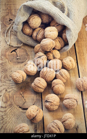 Le noci in un sacchetto su un sfondo di legno Foto Stock