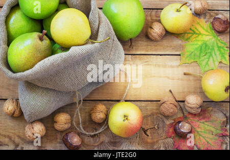 In autunno la composizione di frutta e spezie - pere e noci, foglie di acero su uno sfondo di legno Foto Stock