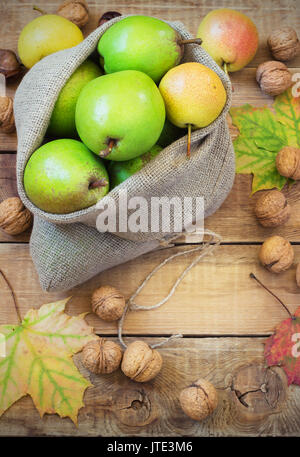 In autunno la composizione di frutta e spezie - pere e noci, foglie di acero su uno sfondo di legno Foto Stock