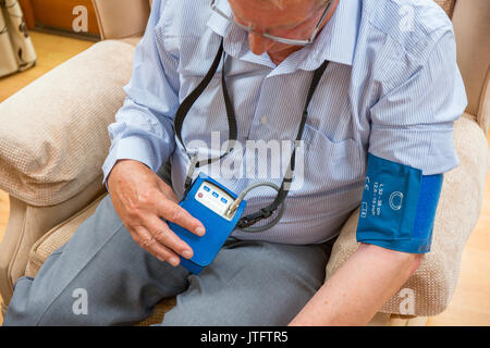Home monitor della pressione del sangue, sfigmomanometro, essendo utilizzato per dare 24 ore che vale la pena di letture. Foto Stock