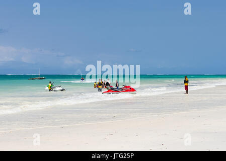 La gente sulla spiaggia e in acqua di scarico sci a getto per l'oceano, Diani, Kenya Foto Stock