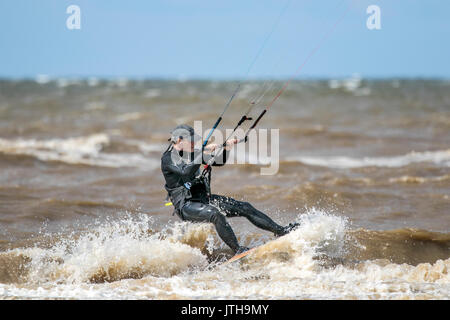 Southport, Merseyside, 9 agosto 2017. Regno Unito Meteo. Un bel pomeriggio di sole e forte vento da nord porta kite boarder fino alla spiaggia per un po' di divertimento nel surf a Southport nel Merseyside. Credito: Cernan Elias/Alamy Live News Foto Stock