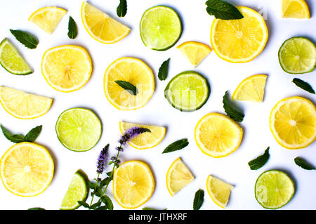 Limone e fettine di lime con foglie di menta su sfondo bianco Foto Stock