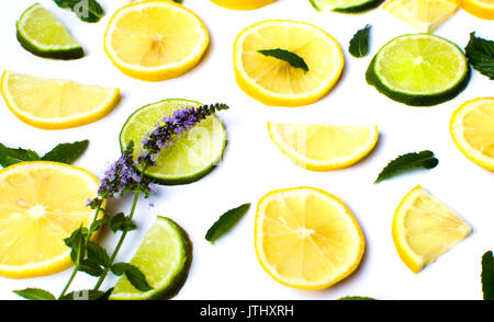 Limone e fettine di lime con foglie di menta su bianco Foto Stock