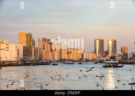 Vista del Dubai Creek con un sacco di gabbiani e barche abra al tramonto, Emirati Arabi Uniti, Emirati arabi uniti Foto Stock