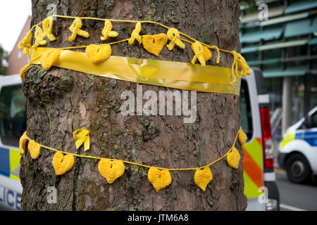 Grenfell Tower, West London. Conseguenze della tragedia. Maglia gialla cuori per onorare il mancante legato attorno ad un albero vicino alla bruciata torre. Foto Stock