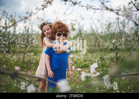 Piccolo Ragazzo e ragazza nel giardino fiorito Foto Stock