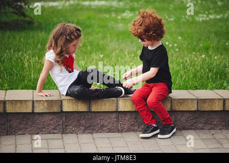 Ragazzo aiuta bambina tie lacci delle scarpe Foto Stock