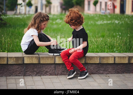 Ragazzo aiuta bambina tie lacci delle scarpe Foto Stock