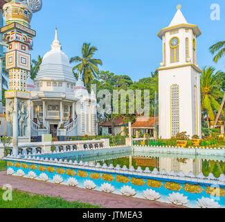 La Scenic torre dell orologio dietro la piscina di Angurukaramulla tempio buddista (Bodhirajaramaya), gli edifici sono decorati con disegni e rilievi di Foto Stock