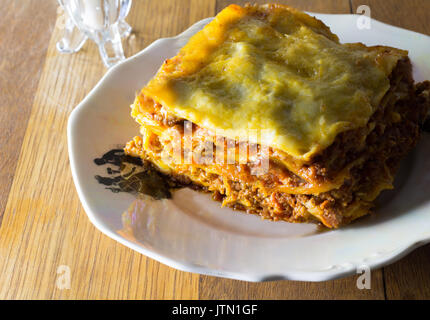 Piastra del singolo che serve di manzo piccante lasagne per cena su tavola in legno rustico Foto Stock