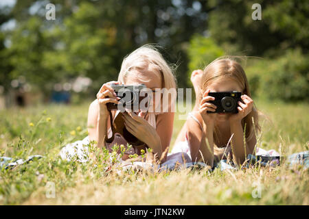 Mamma e figlia di scattare le foto che giace su una coperta nel parco. Foto Stock