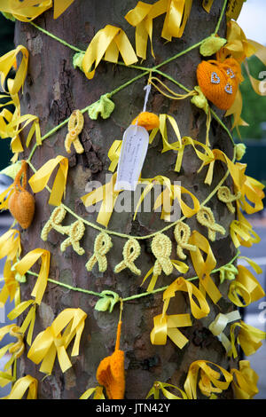 Grenfell Tower, West London. Conseguenze della tragedia. Nastri di colore giallo per onorare il mancante legata intorno a un albero Foto Stock