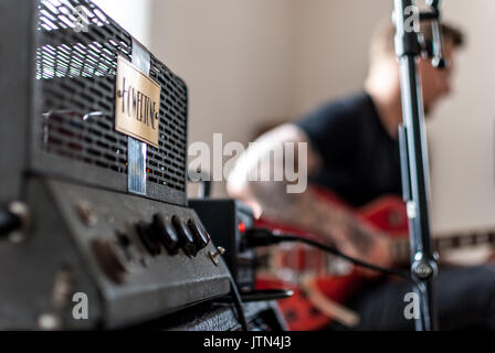 Il chitarrista riproduzione durante una sessione di registrazione attraverso un amplificatore per chitarra Foto Stock
