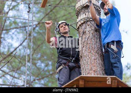 MEZIO, Portogallo - 22 luglio 2017: uomo avventuroso si prepara a una diapositiva in zip fodera attraverso la foresta. Luglio 22, 2017, Mezio, Portogallo. Foto Stock