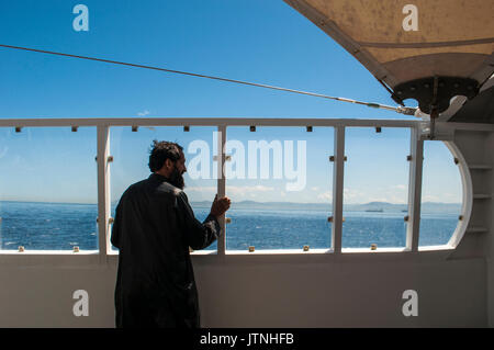 Un uomo musulmano guardando la costa sul traghetto che collega la Spagna al Marocco, nel tratto di mare che si unisce all'Oceano Atlantico al Mar Mediterraneo Foto Stock