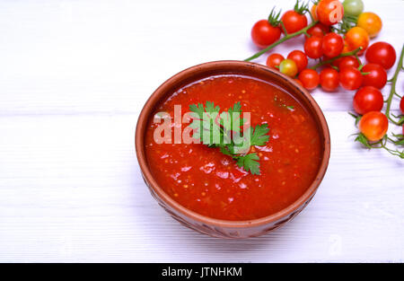 Zuppa di pomodori rossi freschi gazpacho in ceramica piastra marrone su un tavolo bianco, spazio vuoto