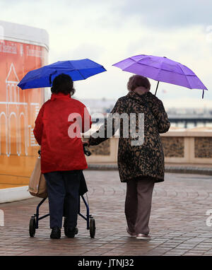 La gente a piedi lungo la passeggiata in Brighton, Sussex, come un giallo allarme meteo per pioggia è stato rilasciato per le parti del Regno Unito. Foto Stock