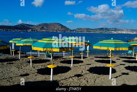 Bellissima spiaggia della baia di Napoli in Italia.Prima del giorno termina nel resort ombrelloni in piedi in spiaggia aggiungendo bellissimi colori del paesaggio Foto Stock