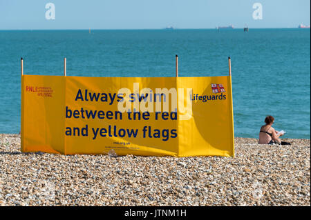 Bagnino RNLI il frangivento di firmare a Southsea beach in Hampshire. Nuotare betweeneo red & bandiere gialle Foto Stock