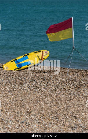 Southsea beach con il rosso e il giallo di sicuro zona di balneazione bandiera con bagnini di salvataggio board. Foto Stock