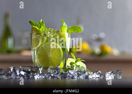 Cocktail con calce , ghiaccio e foglie di menta piperita su una tavola nera . Foto Stock